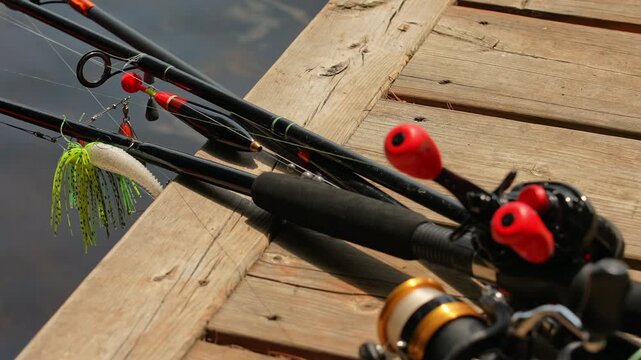 Focus shift on fishing rods lines, bobber and plastic jig with minnow lures. Spinning and casting rods with fishing tackles on boat pier near boat house Slow motion. Family fishing with kids.