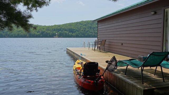 Fully rigger kayak watercraft mooring and tied to boat pier near cottage. Recreational watercraft, kayaking lake during tournament or fishing derby. Kayak water craft equipment for fishing activities.