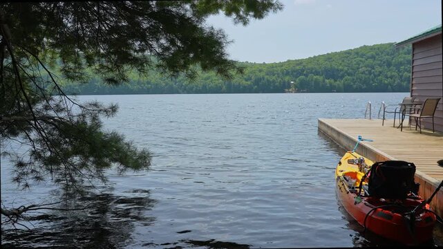 Fully rigger kayak watercraft mooring and tied to boat pier near cottage. Recreational watercraft, kayaking lake during tournament or fishing derby. Kayak water craft equipment for fishing activities.