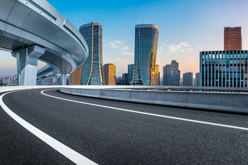 Empty asphalt highway road and city skyline with modern buildings at sunrise in Hangzhou