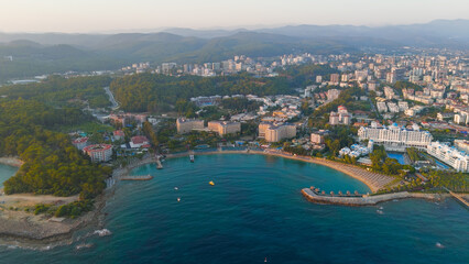 Fototapeta premium Avsallar, Alanya, Turkey. Evening panorama of a resort-lined bay with private beaches, city and mountain views.. Aerial View