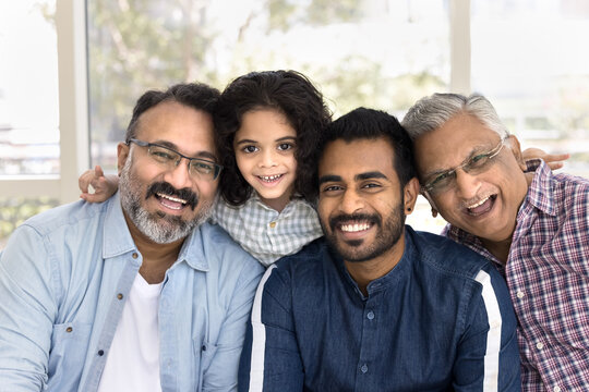 Four generations portrait, little boy posing for photo with great-grandfather, grandpa and young father sit together closely, smiling for camera, exuding warmth, happiness, deep sense of family unity
