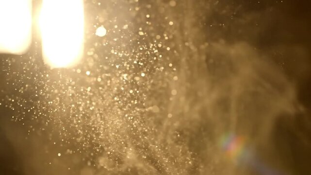 Sparkling dust particles floating in the air illuminated by bright light from above