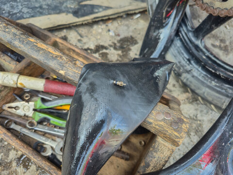 Manual vulcanizing press machine patching a motorcycle inner tube at a traditional roadside repair shop. Old mechanical tool for fixing flat tires in a workshop