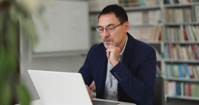 Focused middle-aged 50s business man working online using laptop, search issue solution, making business decision, solving problem, thinking on task or researching, reviewing information in office