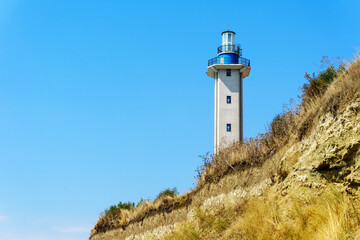 Lighthouse on the hill with blue empty sky