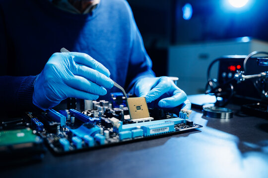 The technician is putting the CPU on the socket of the computer motherboard. electronic engineering electronic repair, electronics measuring and testing, repair