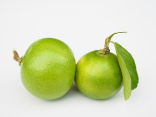 Two fresh, green lemons sit on a white background. They are lemons I grow organically.