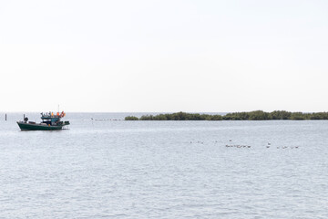 Obraz premium Fishing boat sea island water horizon birds small fishing boat on calm sea with distant island and birds flying peacefully