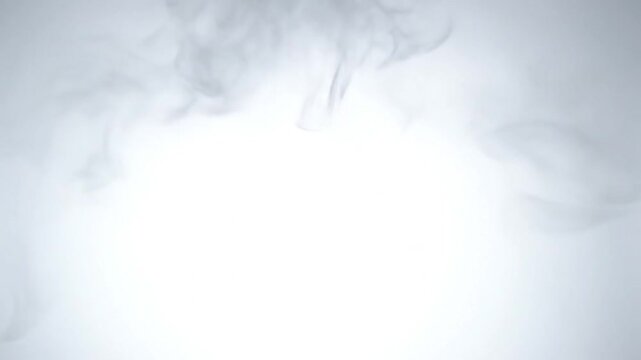 Smoke flowing gently across a soft gray background from an unseen source, captured in a serene close-up view