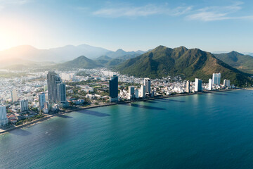 Fototapeta premium Overlooking aerial panorama view city on the gold main resort coast of Southeast Asia in the hot sunny day Nha Trang the mountains is in the distance