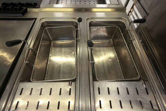 Details with an empty stainless steel professional oil deep fryer in the kitchen of a restaurant