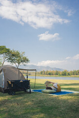 asian couple fun happy and relax with camping and picnic at side of lake with mountain background