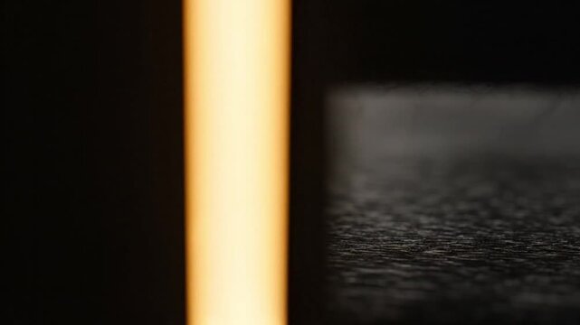 Close-up of a warm light beam on a dark textured surface with a shallow depth of field.