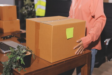 Startup SME small business entrepreneur of freelance Asian woman wearing apron using laptop and box to receive and review orders online to prepare to pack sell to customers, online sme business ideas.