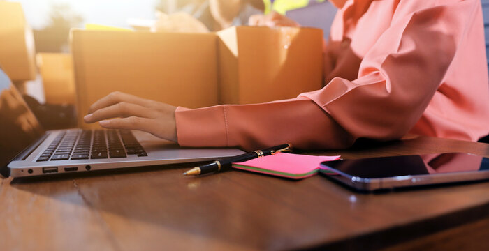 Startup SME small business entrepreneur of freelance Asian woman wearing apron using laptop and box to receive and review orders online to prepare to pack sell to customers, online sme business ideas.