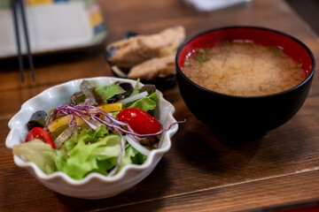 A bowl of salad with miso soup in a black cup, Japanese food. on the wooden table