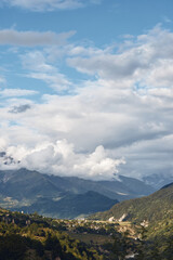 Obraz premium Mountain landscape valley and village under dramatic clouds panoramic nature scene with rolling hills and forest