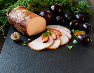 Smoked tenderloin with plums on a dark background