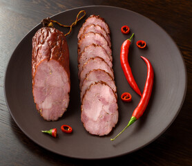 Smoked sausage with red pepper on a dark plate