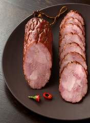 Smoked sausage with red pepper on a dark plate