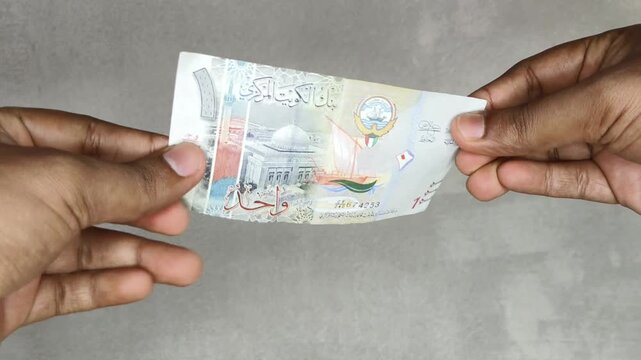 Hand checking kuwaiti dinar (kwd) currency note money for analyzing authenticity due to suspicion of forgery or counterfeit. Kuwait fake money concept. Extreme closeup macro side view.