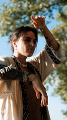 A beautiful brunette dressed in boho style meditates and dances in the forest. A magical ritual takes place against a green forest backdrop.