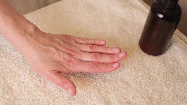 Close up of a woman resting her hand on a towel and examining natural nails, calm home scene focused on manicure care, nail health, skin condition, and routine hand maintenance.