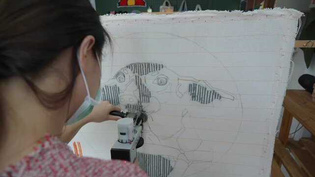 A creative individual works on a textile art project, using a tool to outline an animal design. The vibrant setting reflects artistic inspiration.