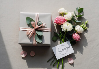 A beautifully wrapped gift and bouquet of flowers for Mother's Day on a white background