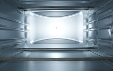 Interior view of an empty clean electric oven with silver metallic walls and metal heating...