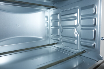 Interior view of an empty clean electric oven with silver metallic walls and metal heating...