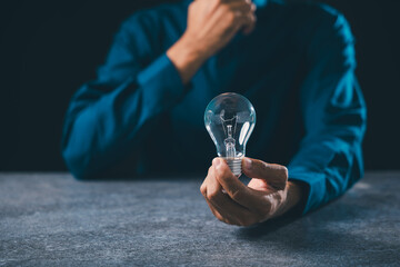 Hand holding lightbulb for idea innovation business concept, inspiration moment shows thinking process with digital power and creative bulb light solutions on dark stone background © sorapop