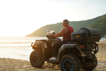 Fototapeta premium A man engages in extreme ATV riding on sand beach early in the morning