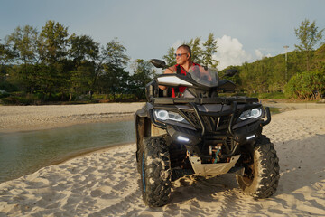 Fototapeta premium A man engages in extreme ATV riding on sand beach early in the morning