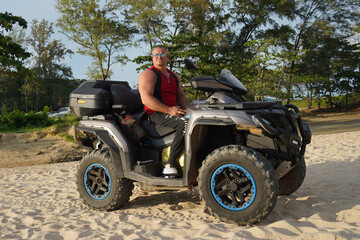 Fototapeta premium A man engages in extreme ATV riding on sand beach early in the morning