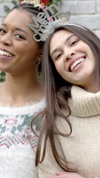 Vertical video: Smiling friends leaning into camera in yard wearing festive headbands and sweaters