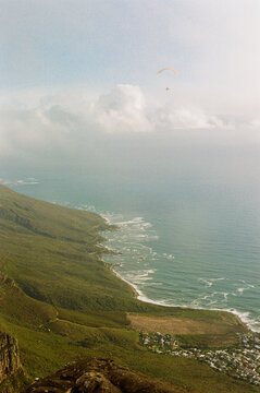 Coastal view from high ground with paragliding activity on clear day