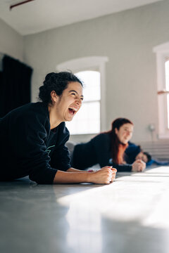 Young women laughing while planking during indoor exercise