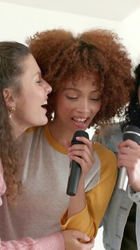 Vertical video: Smiling singer lifting mic urging pals leaning and singing at home in yellow raglan