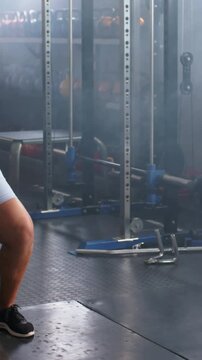 Vertical video: Gripping 5kg kettlebell, woman in blue top swinging, hinging for fitness at gym