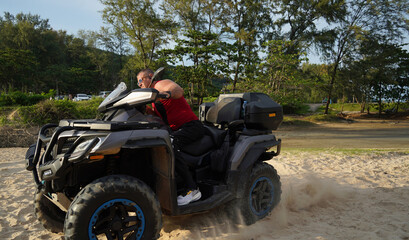 Fototapeta premium A man engages in extreme ATV riding on sand beach early in the morning