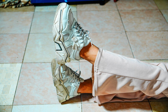 view of a woman's feet wearing white chunky sneakers with a thick sole design and patterned laces and a background for text space. close up of a woman's feet wearing sneakers and athletic shoes.