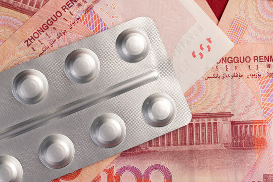 Chinese cash for one hundred yuan and pills in a packaged blister, medicines and red cash with a face value of 100 yuan are lying together.