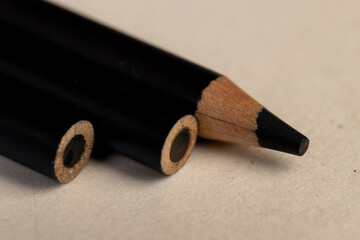 a row of black wooden pencils folded on cheap loose paper, wooden pencils with lead for drawing or...