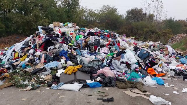Large mountain of worn clothing and garbage. Concept of waste, pollution, and irresponsible consumption, 4k