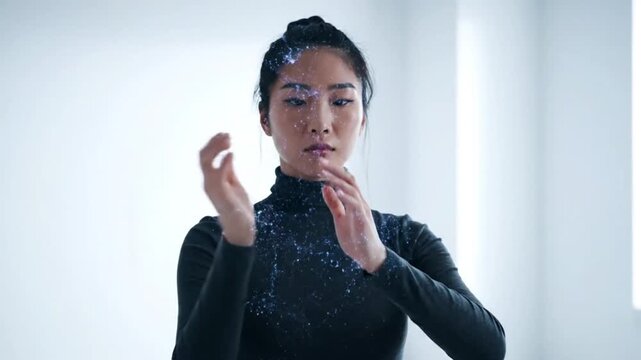 Asian Woman in Black Turtleneck Manipulating Digital Blue Particle Energy and Holographic Sparkles with Her Hands in a Clean White Studio Background.