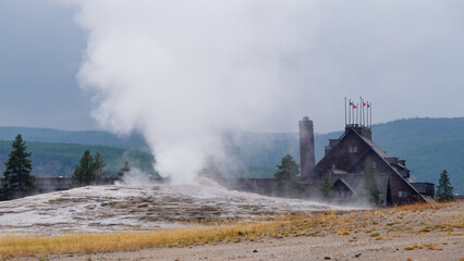 View of the Old Faithful Inn and steaming geyser eruption in Yellowstone National Park, Wyoming, USA