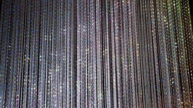 Shimmering vertical light curtain glittering beads iridescent glow cinematic backdrop