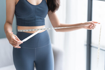 Asian healthy woman dieting Weight loss. Slim woman measuring waist with measure tape after diet at...